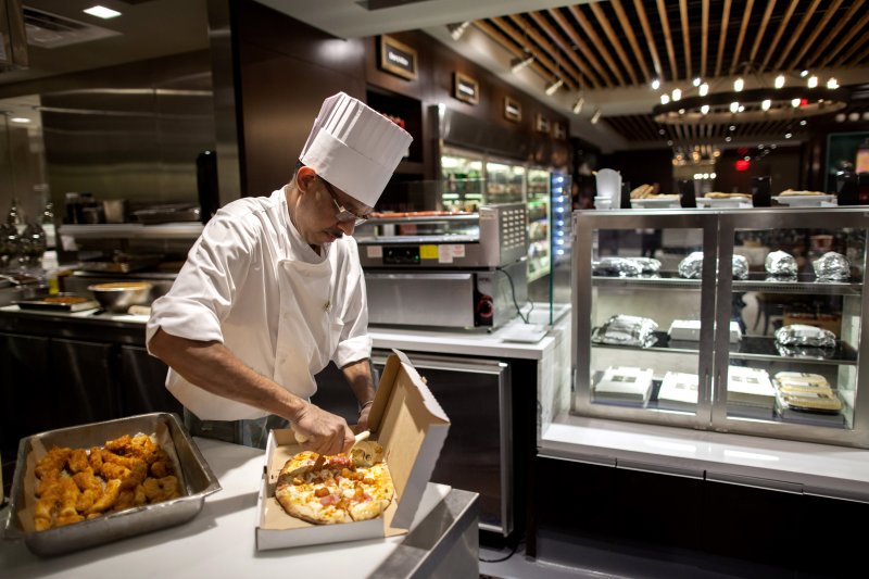 Cook Suresh Deshbhandari packages a flatbread pizza at Herb N' Kitchen, a new dining area at the Hilton Midtown in New York, NY on Sept. 17, 2013. The restaurant, which emphasizes ready-to-go and quickly prepared made-to-order foods, opened in July. 

CREDIT: Brian Harkin for The Wall Street Journal
FIXDECODE_Hilton